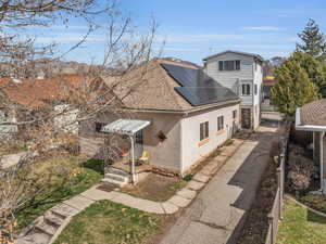 View of front of property with driveway, fence, roof with shingles, brick siding, and solar panels