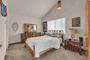 Carpeted bedroom featuring lofted ceiling and baseboards