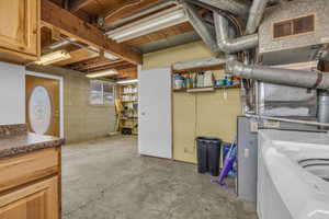 Below grade area featuring concrete block wall, washer / clothes dryer, and visible vents