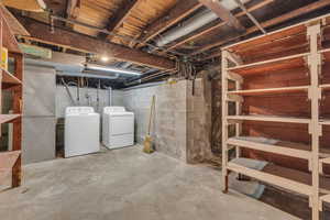 Unfinished basement featuring washing machine and clothes dryer