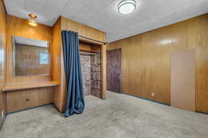 Unfurnished bedroom featuring carpet floors and wood walls