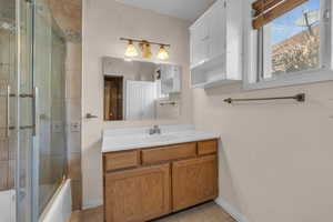 Bathroom featuring vanity, tile patterned floors, combined bath / shower with glass door, and baseboards