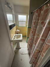 Full bathroom with a sink, a wainscoted wall, a shower with curtain, and tile walls