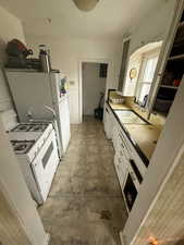 Kitchen with glass insert cabinets, light floors, white gas range, white cabinetry, and a sink