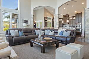 Living room with ornate columns, arched walkways, a towering ceiling, recessed lighting, and dark carpet