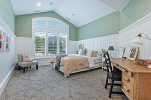 Carpeted bedroom with visible vents, wainscoting, and lofted ceiling