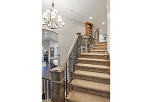 Stairs with recessed lighting, arched walkways, wood finished floors, a chandelier, and a high ceiling