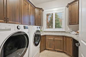 Washroom featuring cabinet space, separate washer and dryer, and light tile patterned floors