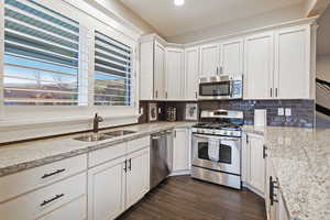 Kitchen featuring appliances with stainless steel finishes, a sink, tasteful backsplash, white cabinetry, and recessed lighting