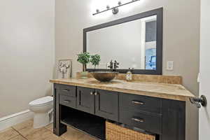 Bathroom featuring toilet, vanity, baseboards, and tile patterned floors