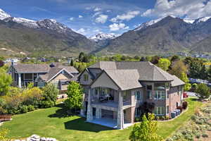 Back of house with a patio area, a lawn, central AC, and a mountain view