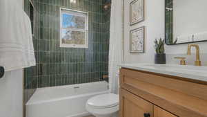 Full bathroom featuring vanity, toilet, and shower / tub combo with curtain