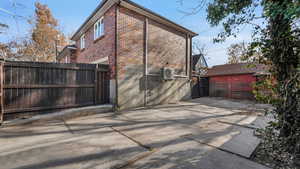 View of side of property featuring brick siding, ac unit, a patio area, and fence