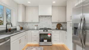 Kitchen featuring a sink, stainless steel appliances, tasteful backsplash, and light wood-style floors