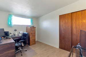 Bedroom with light wood-style flooring, a textured ceiling, and baseboards