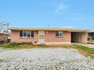 Ranch-style house with an attached carport, central air condition unit, brick siding, and driveway