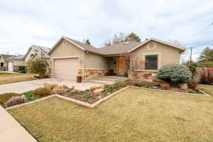 Single story home with a front lawn, a garage, driveway, and stucco siding