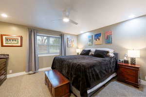 Bedroom with baseboards, light colored carpet, and a ceiling fan