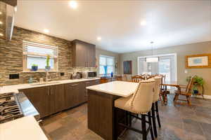 Kitchen with stainless steel microwave, light countertops, decorative backsplash, and a sink