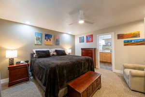 Bedroom featuring light colored carpet, baseboards, ensuite bathroom, and ceiling fan