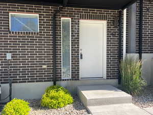 View of exterior entry featuring central AC unit and brick siding