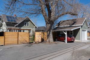 View of front of house featuring a garage, roof with shingles, driveway, and fence