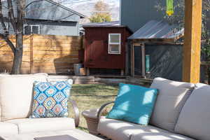 View of patio with an outbuilding, outdoor lounge area, and fence