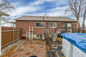 Back of house featuring a patio area, fence, brick siding, and roof with shingles