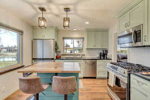 Kitchen with butcher block countertops, appliances with stainless steel finishes, light wood-style floors, plenty of natural light, and a sink