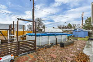 View of swimming pool featuring a fenced in pool, an outdoor structure, a fenced backyard, and a storage shed