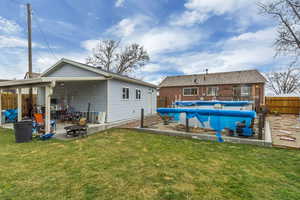 Rear view of property featuring fence, a fenced in pool, an outdoor fire pit, a yard, and a patio area
