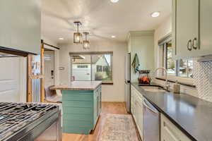 Kitchen with light wood-type flooring, a sink, a barn door, appliances with stainless steel finishes, and wooden counters