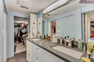 Bathroom with double vanity, tile patterned flooring, a walk in closet, and a sink