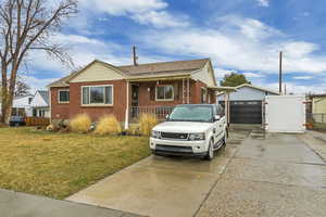 View of front of home with fence, driveway, roof with shingles, a front lawn, and brick siding