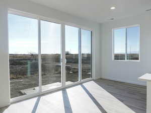 Empty room featuring healthy amount of natural light, wood finished floors, recessed lighting, and baseboards