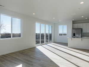 Unfurnished living room featuring recessed lighting, baseboards, and wood finished floors
