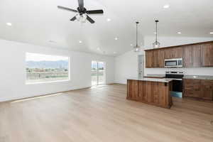 Kitchen featuring appliances with stainless steel finishes, light countertops, open floor plan, lofted ceiling, and a kitchen island