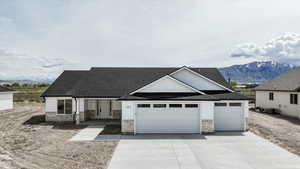View of front of house with concrete driveway, roof with shingles, an attached garage, and stone siding