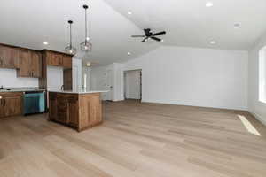 Kitchen featuring light countertops, vaulted ceiling, light wood finished floors, and dishwasher