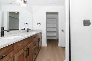 Full bathroom featuring double vanity, visible vents, a sink, and wood finished floors