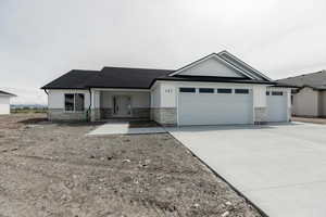 View of front of home featuring concrete driveway, roof with shingles, stone siding, and a garage
