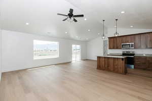 Kitchen featuring appliances with stainless steel finishes, recessed lighting, open floor plan, a kitchen island, and vaulted ceiling
