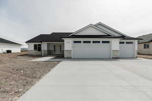 Craftsman inspired home featuring an attached garage, driveway, central AC, and stone siding
