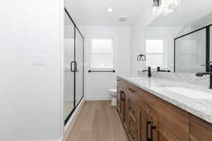 Bathroom with baseboards, a shower stall, a sink, and wood finished floors