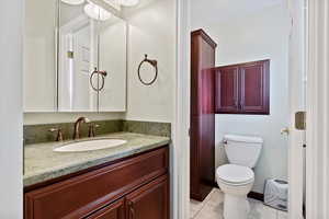 Bathroom with tile patterned flooring, toilet, vanity, and baseboards