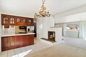 Kitchen with glass insert cabinets, built in microwave, light colored carpet, a peninsula, and stainless steel fridge