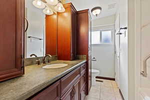 Bathroom featuring tile patterned floors, visible vents, toilet, and vanity