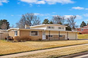 View of front of property with a porch, a chimney, a front lawn, a garage, and brick siding