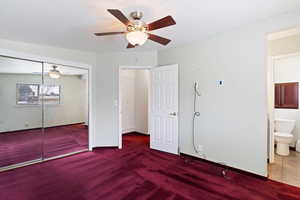 Unfurnished bedroom with baseboards, ceiling fan, carpet, a closet, and ensuite bath