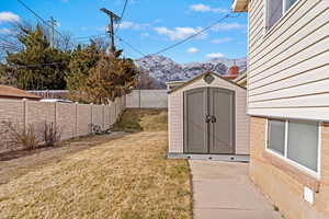 View of yard with an outbuilding, a fenced backyard, a mountain view, and a shed